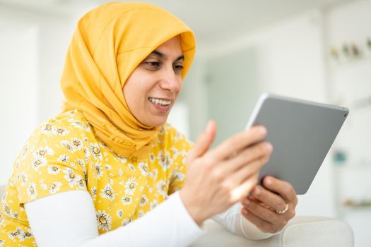 Muslim woman working on tablet at her home