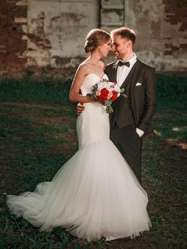 in full growth.the bride with a wedding bouquet and the groom standing near the old manor.