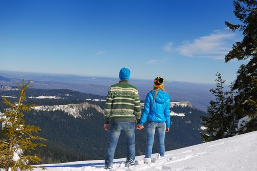 Happy young couple has fun on fresh snow at beautiful winter sunny day on vacation