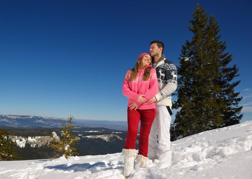 Happy young couple has fun on fresh snow at beautiful winter sunny day on vacation