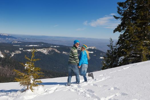 Happy young couple has fun on fresh snow at beautiful winter sunny day on vacation