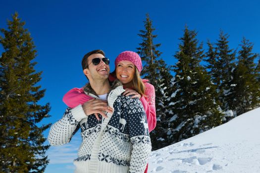 Happy young couple has fun on fresh snow at beautiful winter sunny day on vacation