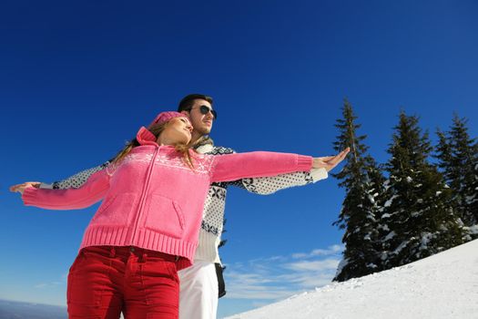 Happy young couple has fun on fresh snow at beautiful winter sunny day on vacation