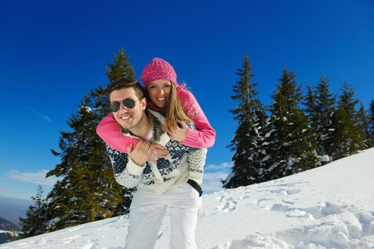 Happy young couple has fun on fresh snow at beautiful winter sunny day on vacation