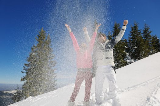 Happy young couple has fun on fresh snow at beautiful winter sunny day on vacation