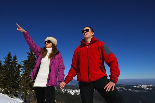 Happy young couple has fun on fresh snow at beautiful winter sunny day on relaxing vacation