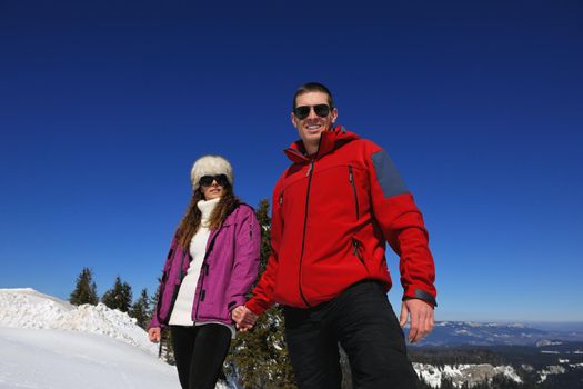 Happy young couple has fun on fresh snow at beautiful winter sunny day on relaxing vacation