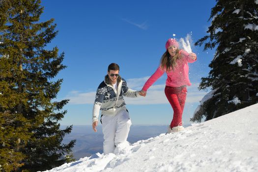 Happy young couple has fun on fresh snow at beautiful winter sunny day on vacation