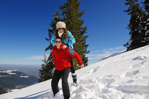 Happy young couple has fun on fresh snow at beautiful winter sunny day on vacation