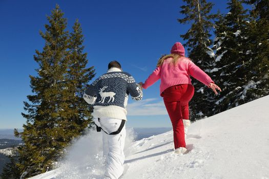 Happy young couple has fun on fresh snow at beautiful winter sunny day on vacation