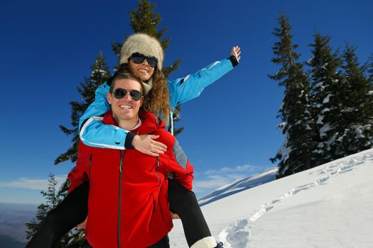 Happy young couple has fun on fresh snow at beautiful winter sunny day on relaxing vacation