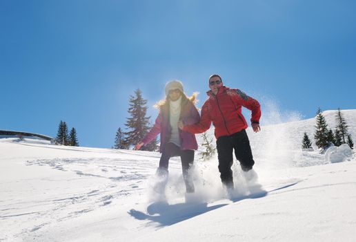 Happy young couple has fun on fresh snow at beautiful winter sunny day on relaxing vacation