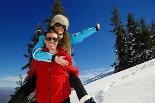 Happy young couple has fun on fresh snow at beautiful winter sunny day on vacation