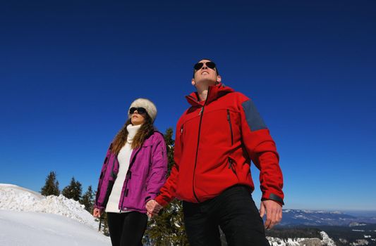 Happy young couple has fun on fresh snow at beautiful winter sunny day on relaxing vacation