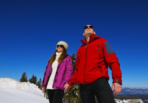 Happy young couple has fun on fresh snow at beautiful winter sunny day on relaxing vacation