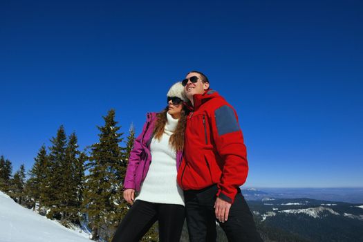 Happy young couple has fun on fresh snow at beautiful winter sunny day on vacation