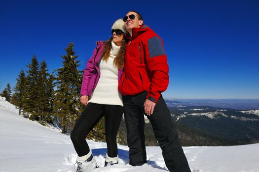 Happy young couple has fun on fresh snow at beautiful winter sunny day on vacation