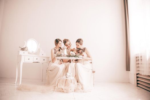 bride and her friends sitting at the festive table in a stylish boudoir.