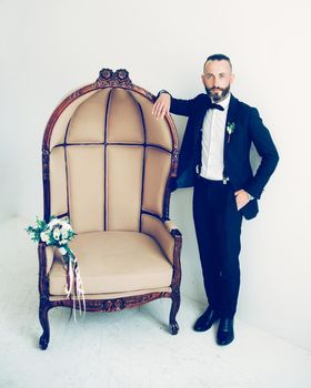 elegant groom standing near the chair in the hotel room. photo with copy space