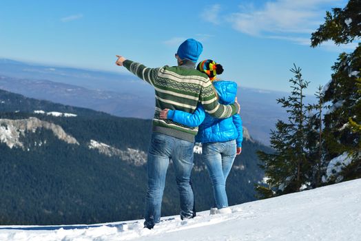 Happy young couple has fun on fresh snow at beautiful winter sunny day on vacation