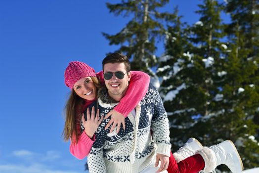 Happy young couple has fun on fresh snow at beautiful winter sunny day on vacation