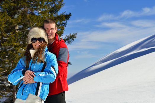 Happy young couple has fun on fresh snow at beautiful winter sunny day on relaxing vacation