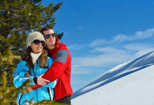 Happy young couple has fun on fresh snow at beautiful winter sunny day on relaxing vacation