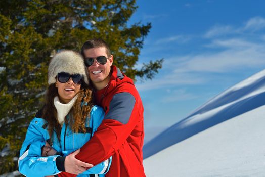Happy young couple has fun on fresh snow at beautiful winter sunny day on vacation