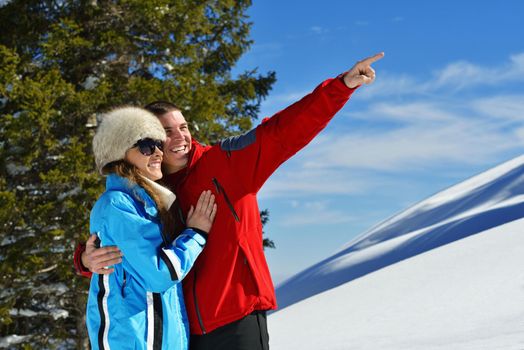 Happy young couple has fun on fresh snow at beautiful winter sunny day on relaxing vacation