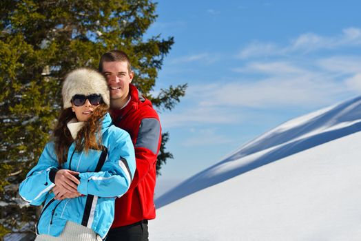 Happy young couple has fun on fresh snow at beautiful winter sunny day on relaxing vacation