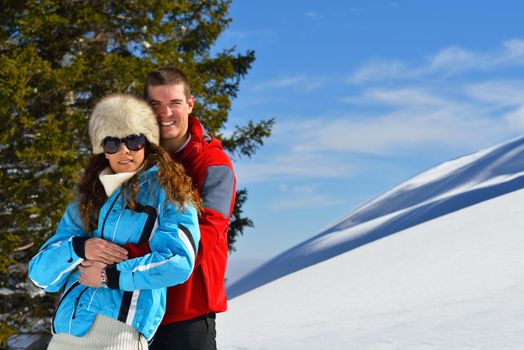 Happy young couple has fun on fresh snow at beautiful winter sunny day on relaxing vacation