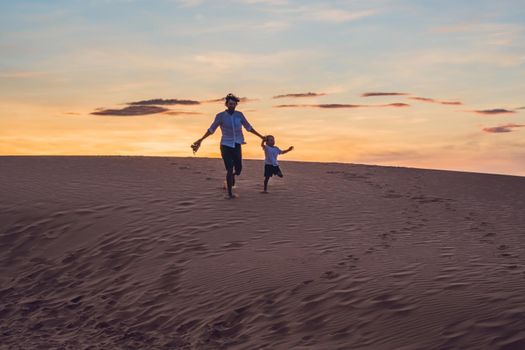 Father and son at the red desert at dawn. Traveling with children concept.