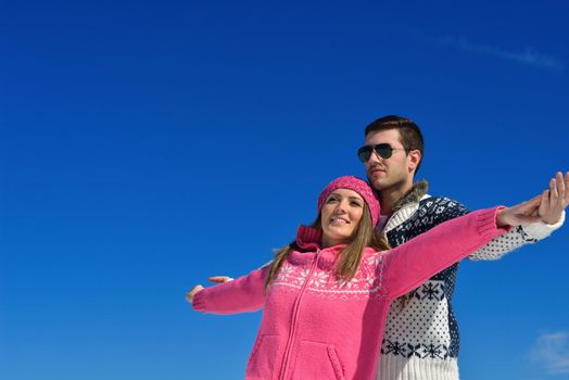 Happy young couple has fun on fresh snow at beautiful winter sunny day on vacation