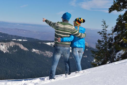 Happy young couple has fun on fresh snow at beautiful winter sunny day on vacation