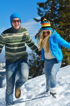 Happy young couple has fun on fresh snow at beautiful winter sunny day on vacation