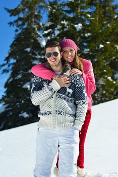 Happy young couple has fun on fresh snow at beautiful winter sunny day on vacation