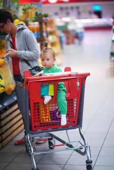 young mother with baby in shopping mall supermarket store buying food and grocery