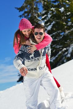 Happy young couple has fun on fresh snow at beautiful winter sunny day on vacation