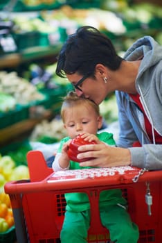 young mother with baby in shopping mall supermarket store buying food and grocery