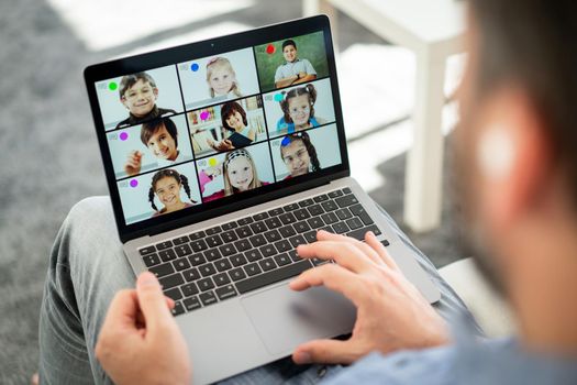 Male teacher having online conference with school children working at home