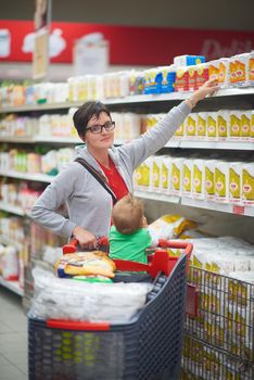 young mother with baby in shopping mall supermarket store buying food and grocery