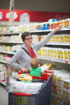 young mother with baby in shopping mall supermarket store buying food and grocery