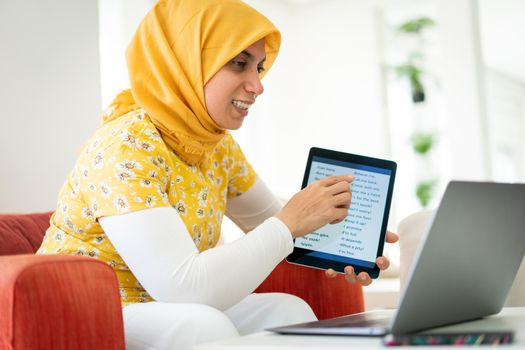 Muslim woman teaching on tablet at home today