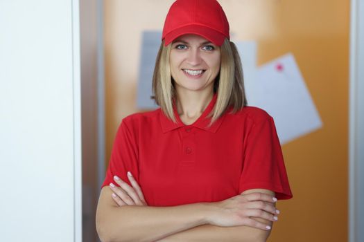 Portrait of happy blonde lady courier in red shirt and cap uniform. Positive mood, best worker of year. Delivery service, shipping, private courier concept