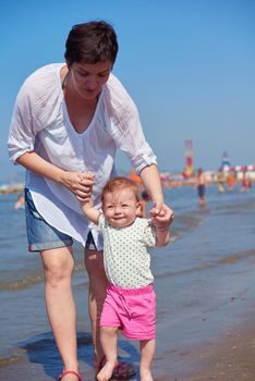 happy mom and baby on beach  have fun while learning to walk and  make first steps