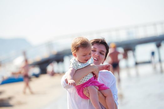 happy mom and baby on beach  have fun while learning to walk and  make first steps