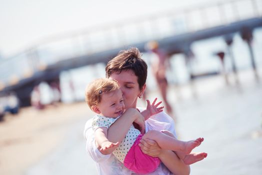 happy mom and baby on beach  have fun while learning to walk and  make first steps