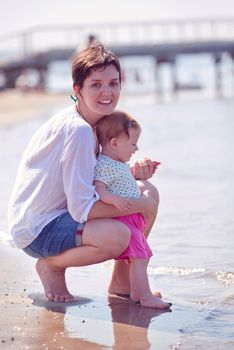 happy mom and baby on beach  have fun while learning to walk and  make first steps