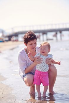 happy mom and baby on beach  have fun while learning to walk and  make first steps