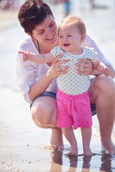 happy mom and baby on beach  have fun while learning to walk and  make first steps